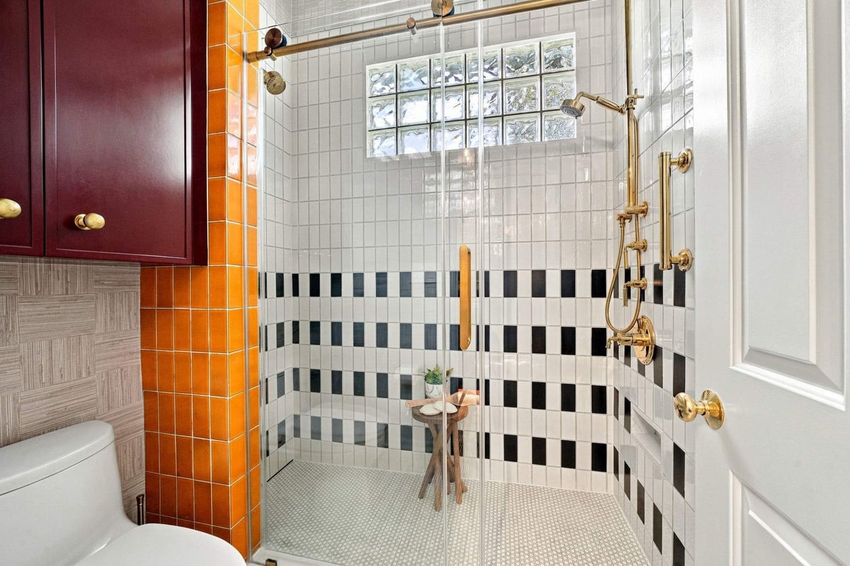 Shavano Park guest bathroom remodel with colorful orange tile, black-and-white shower tile, and gold fixtures.