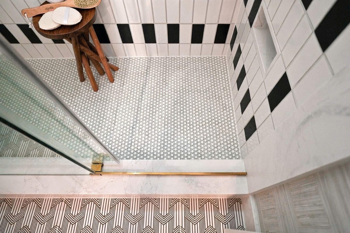 White penny tile shower floor with black-and-white patterned wall tile and glass shower enclosure in a Shavano Park bathroom remodel.