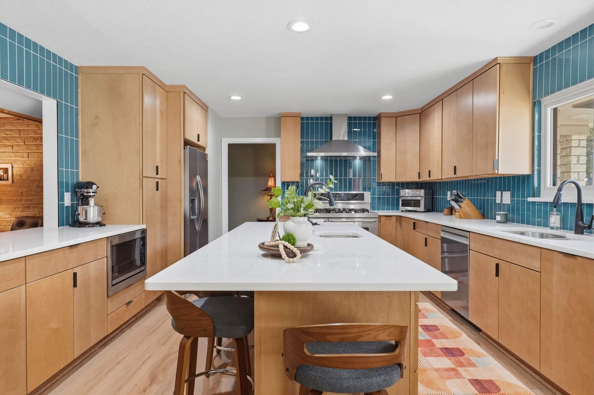 Mid-century modern kitchen with wood cabinets, teal tile and large white island