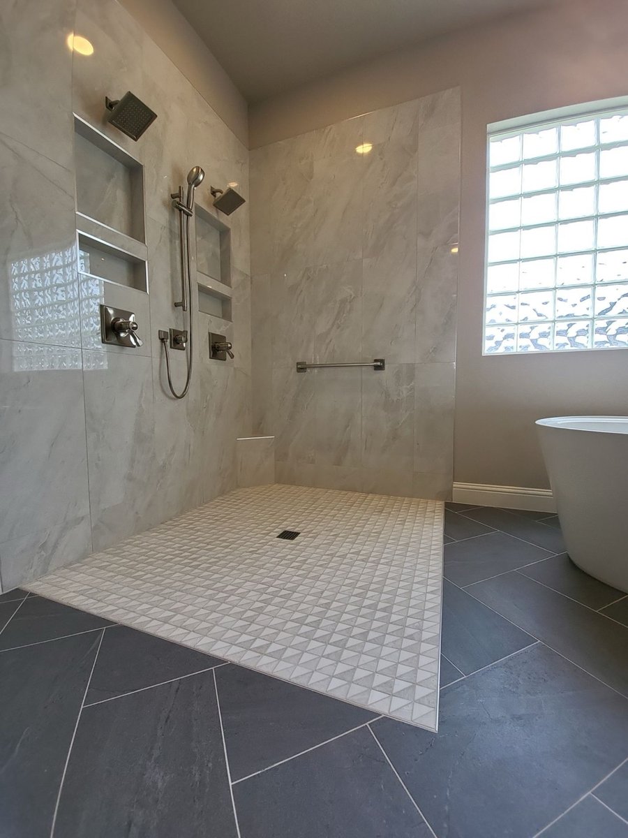 Walk-in shower with dual heads and freestanding tub by glass block window