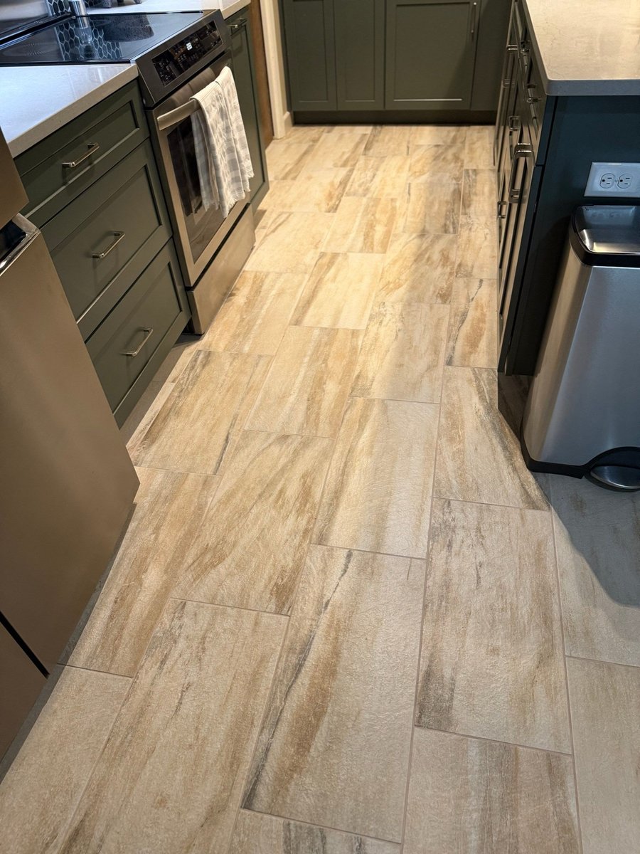 Plank-tile kitchen floor between green cabinets and stainless trash can