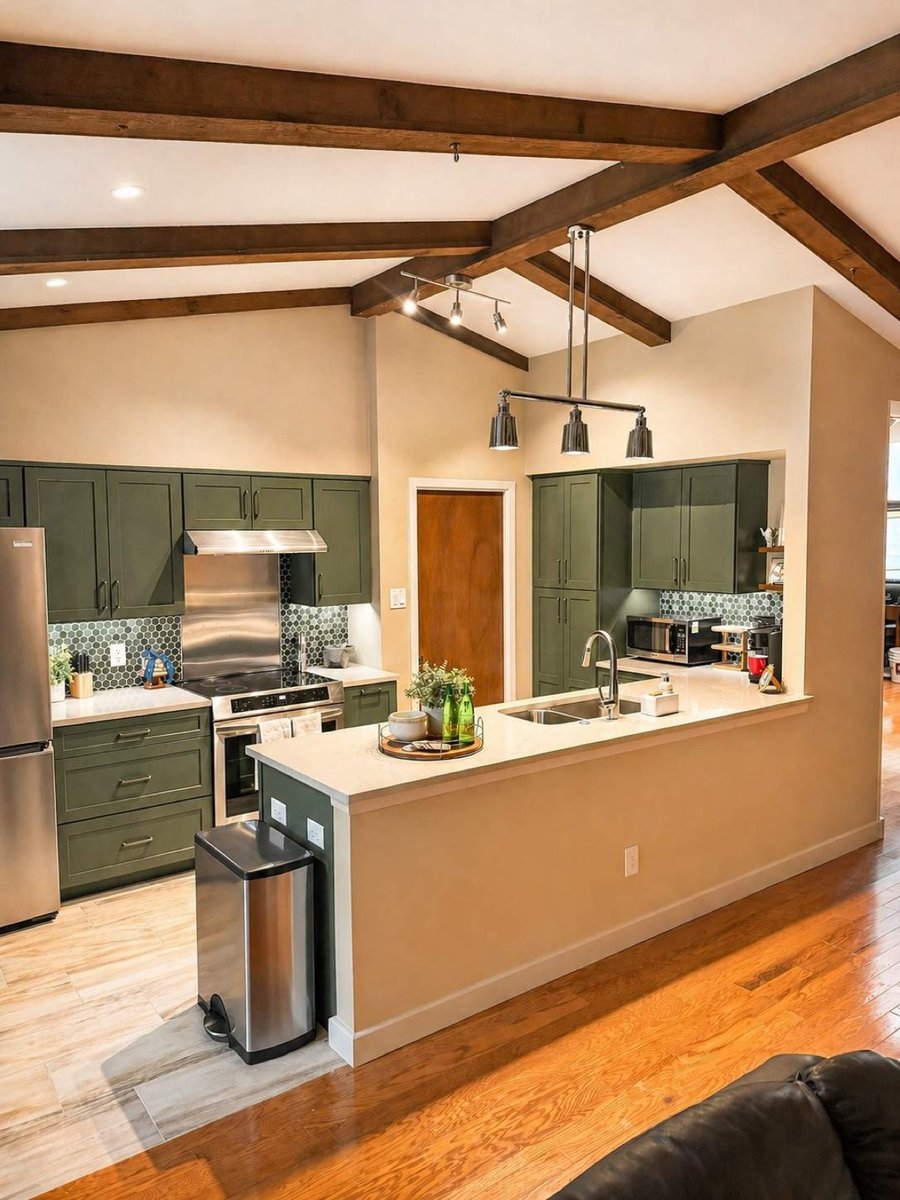 Open kitchen with green cabinets, wood ceiling beams and peninsula sink