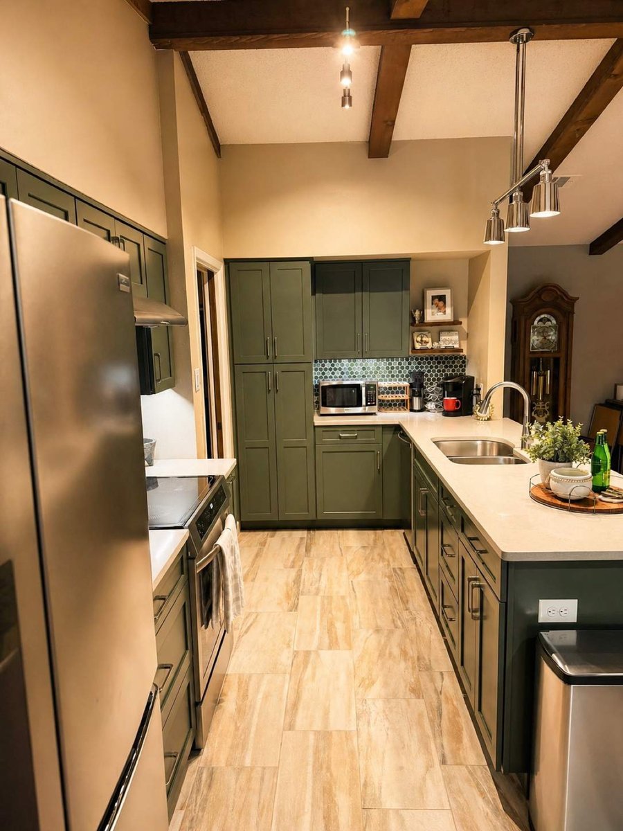 Galley kitchen with green cabinets, exposed beams and quartz peninsula