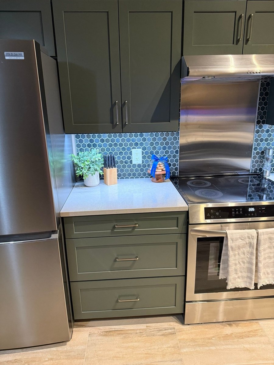 Green cabinets, blue hexagon backsplash and stainless range with knife block