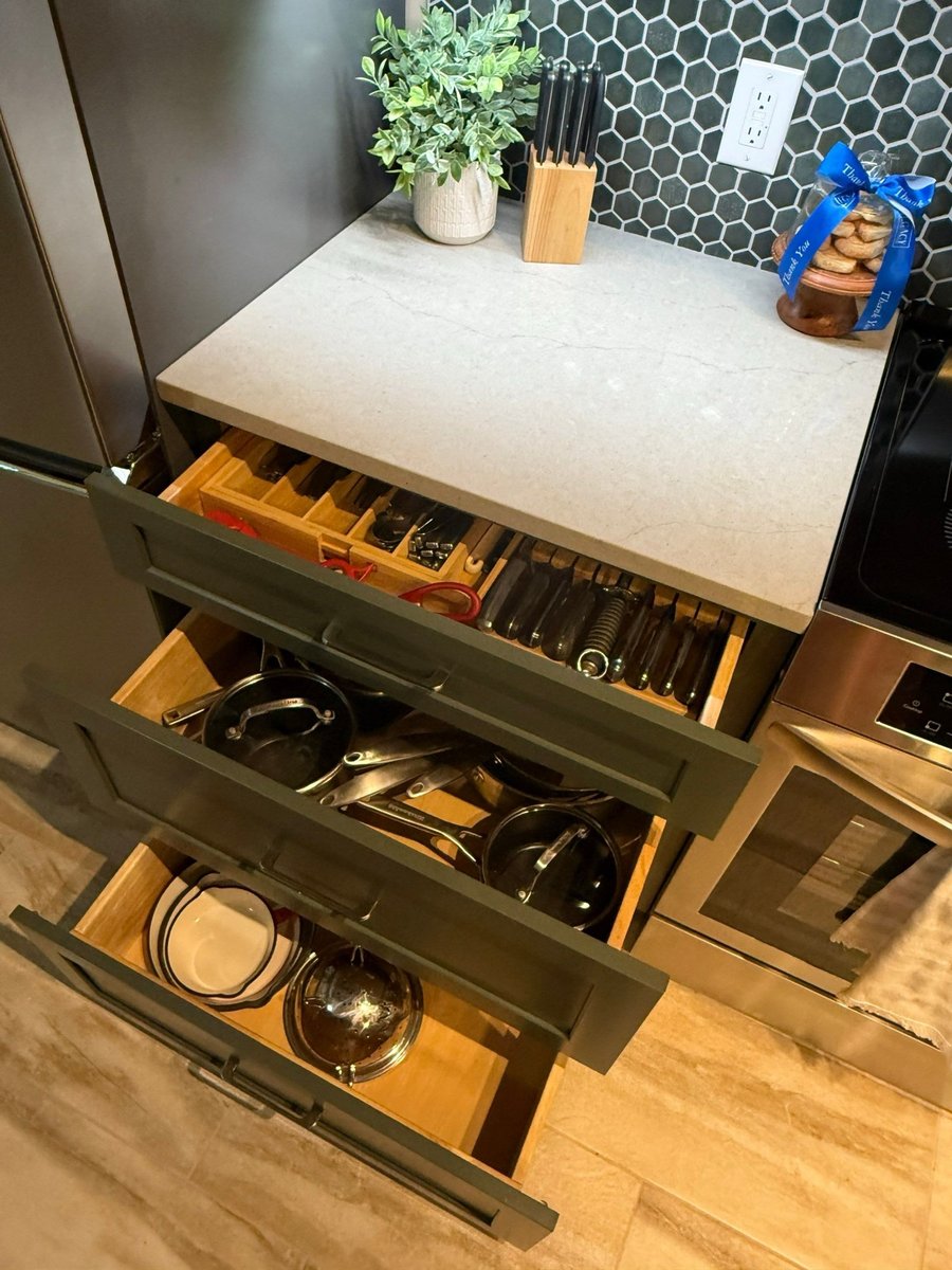 Open green drawers showing organized utensils, pots and dishes