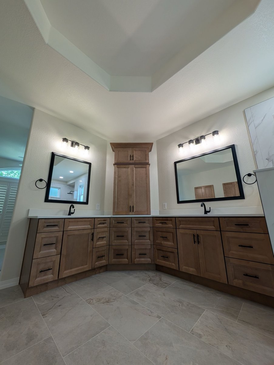 Stained wood double vanity with corner tower cabinet and black-framed mirrors