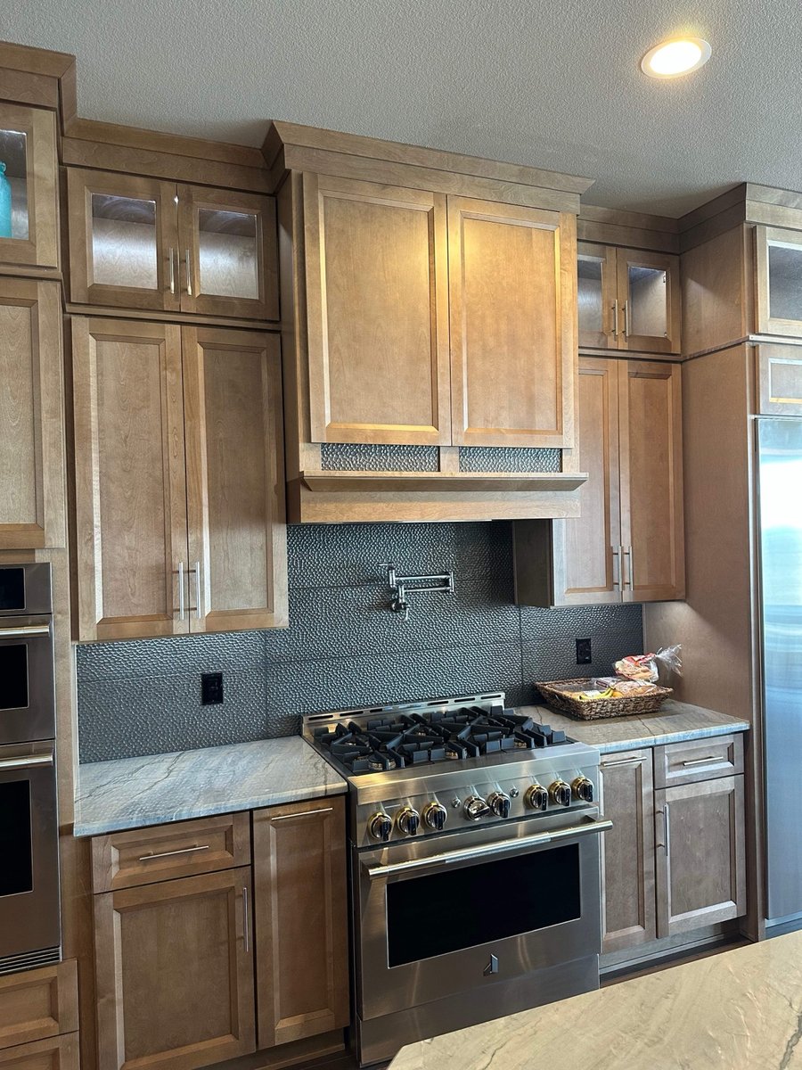 Maple cabinetry and stainless range with charcoal mosaic backsplash and quartzite counters