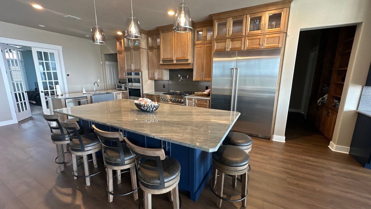 Open kitchen with maple cabinets, stainless appliances, and quartzite island seating six