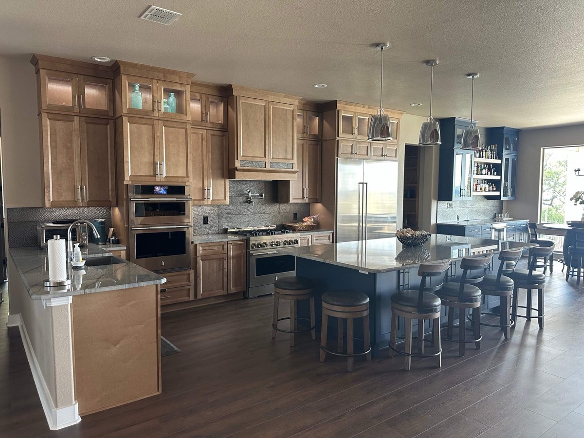 Maple cabinetry, double wall ovens, and gas range with charcoal mosaic backsplash