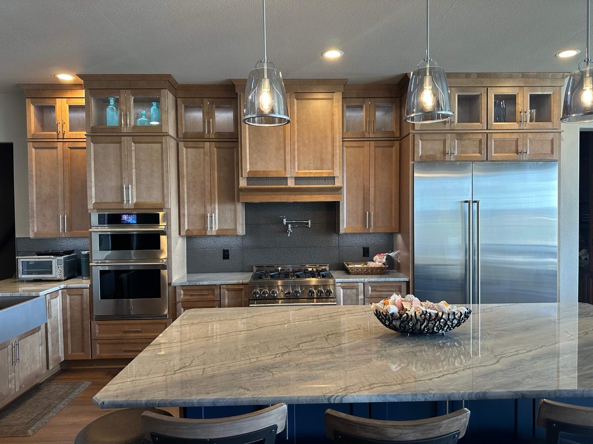 Maple kitchen with pendant lights, stainless refrigerator, and quartzite island bowl