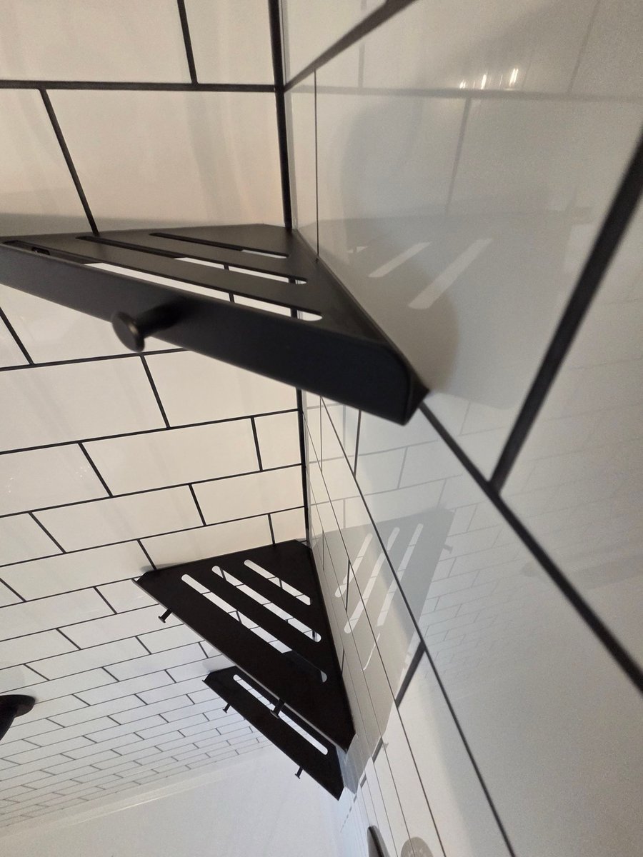 Black corner shower shelves mounted on glossy white subway tile