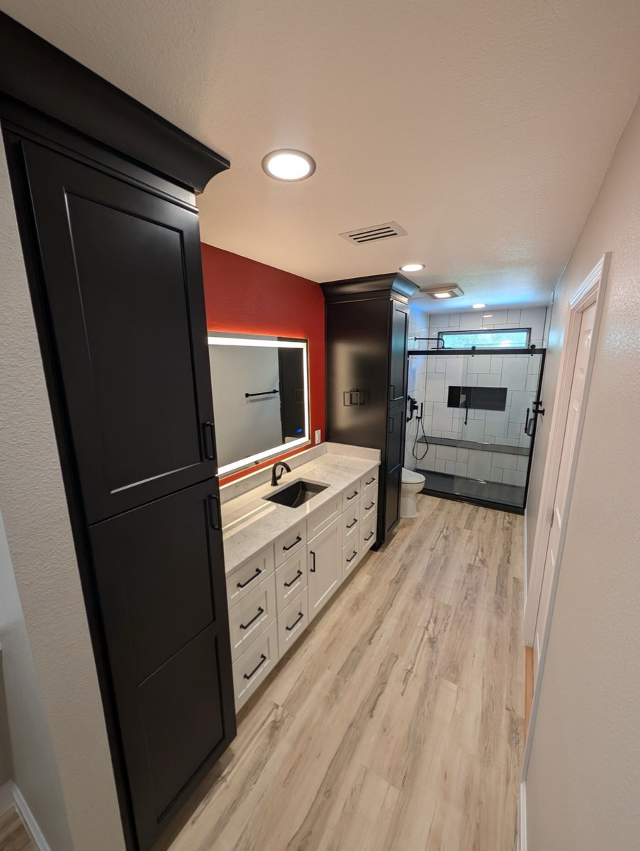 Narrow bathroom with white vanity, black storage towers, and white subway tile shower