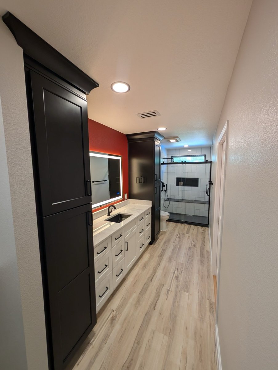 White vanity and black cabinets leading to subway-tiled walk-in shower