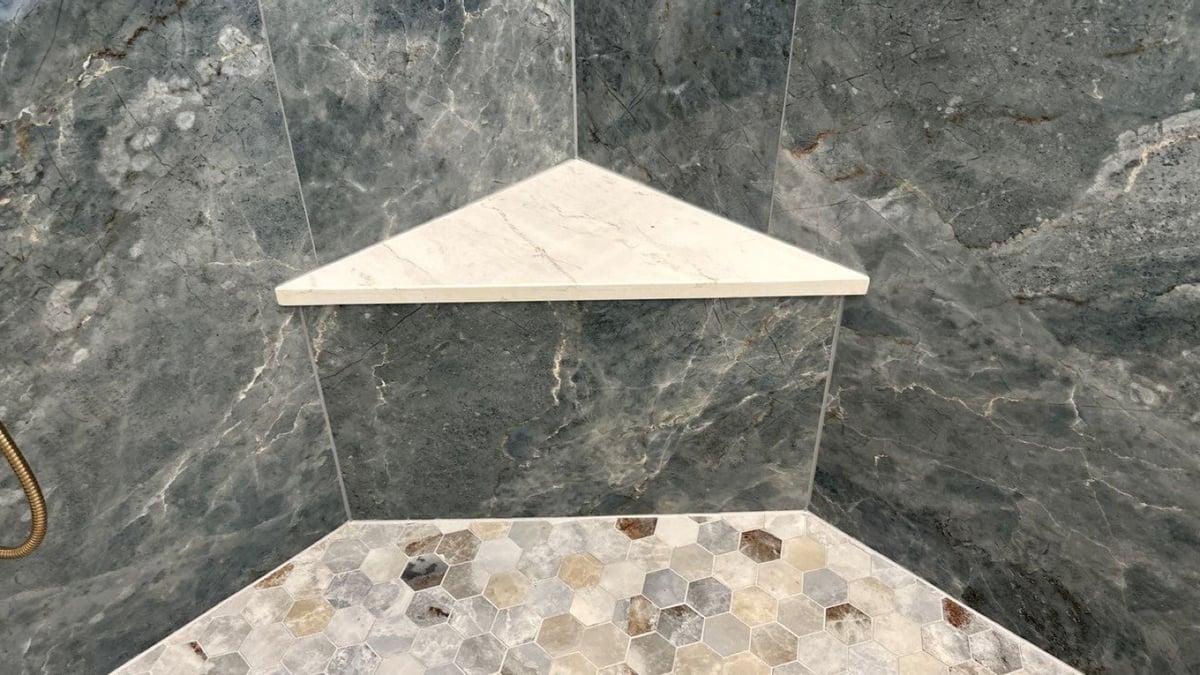 Shower corner shelf and hexagon mosaic floor against dark gray marble tile