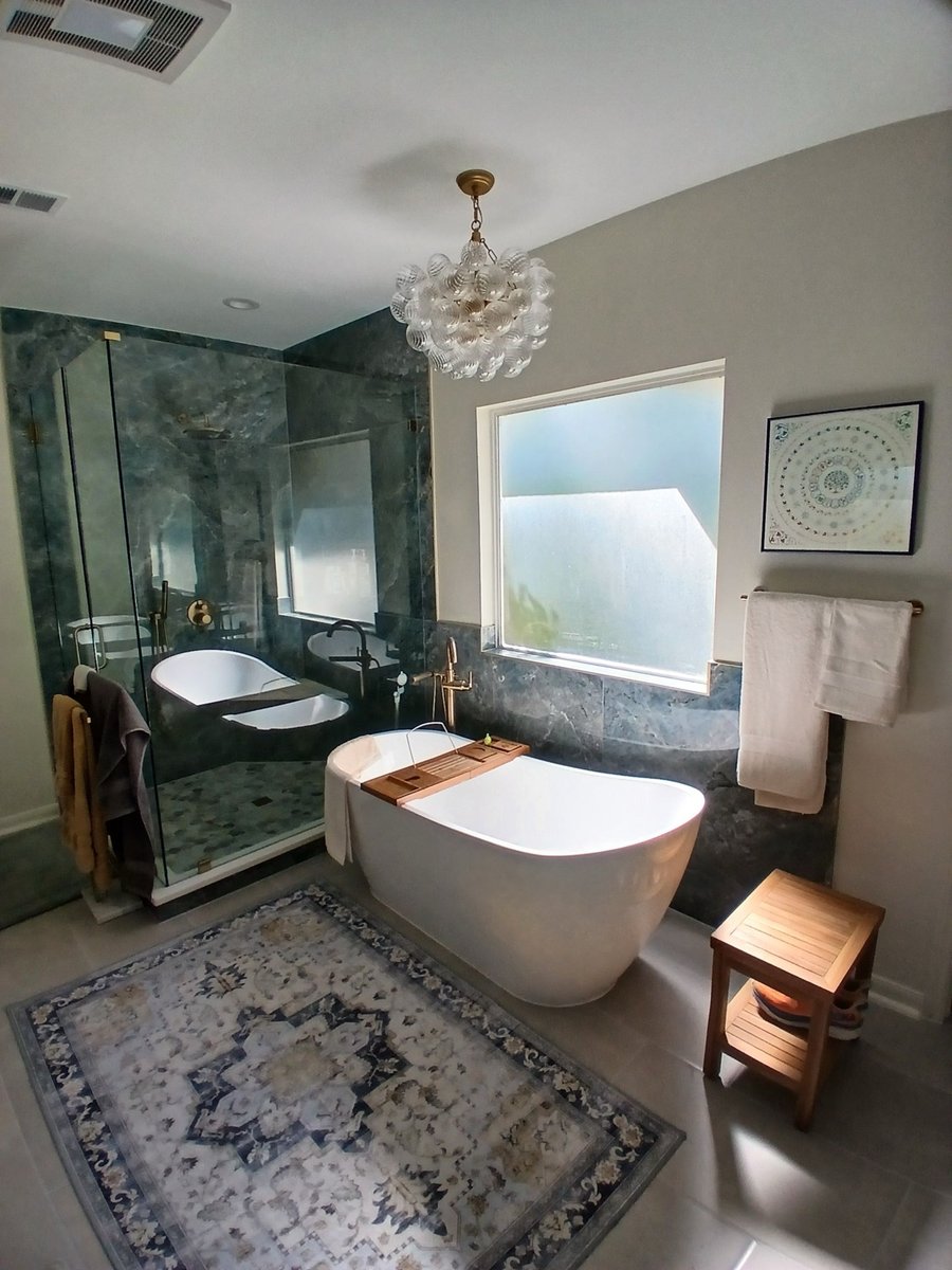 Master bathroom with glass shower, white soaking tub, and bubble chandelier