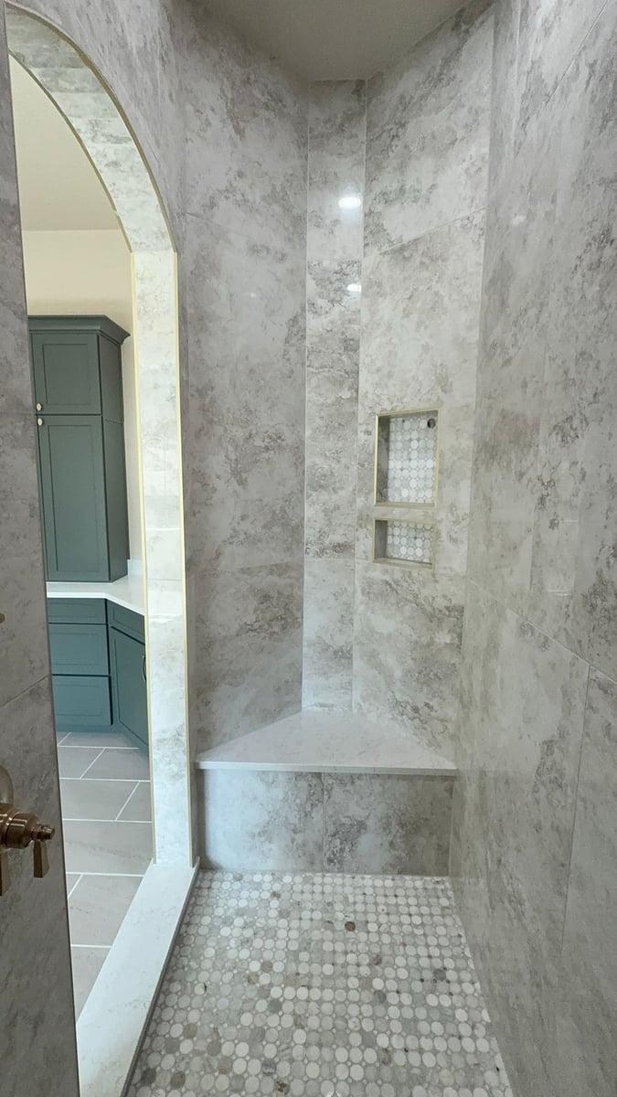 Tall gray marble shower with corner bench, niche and penny tile floor