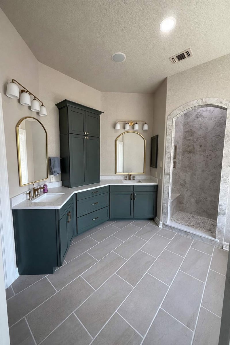 Master bath with deep green cabinets, arched mirrors and arched gray marble shower