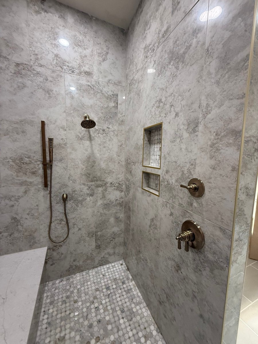 Gray marble shower wall with rainfall head, handheld sprayer and recessed niches