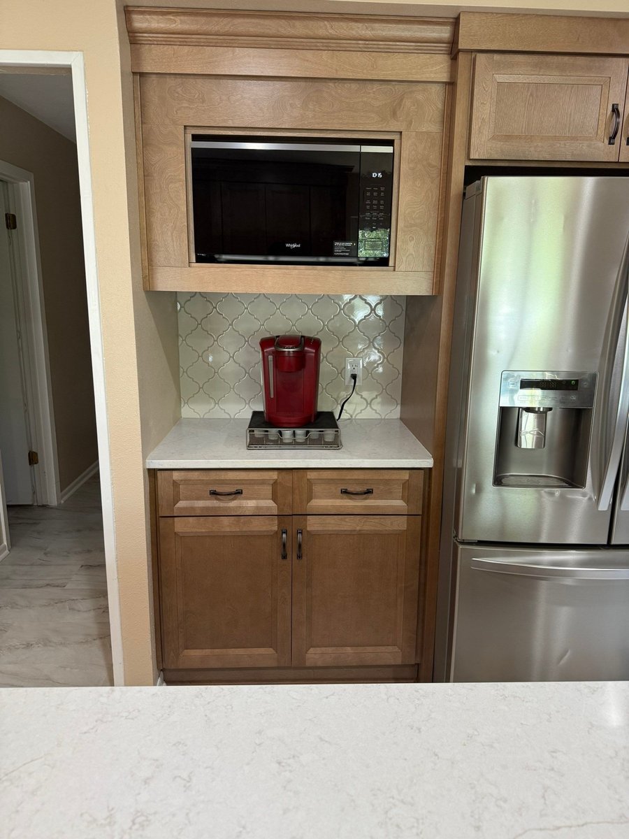 Coffee bar nook with stained wood cabinets, microwave, and arabesque tile backsplash