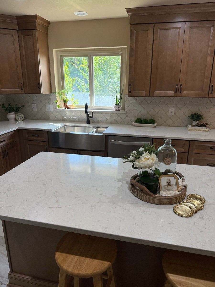 Stained wood kitchen with white quartz island, farmhouse sink, and window backsplash