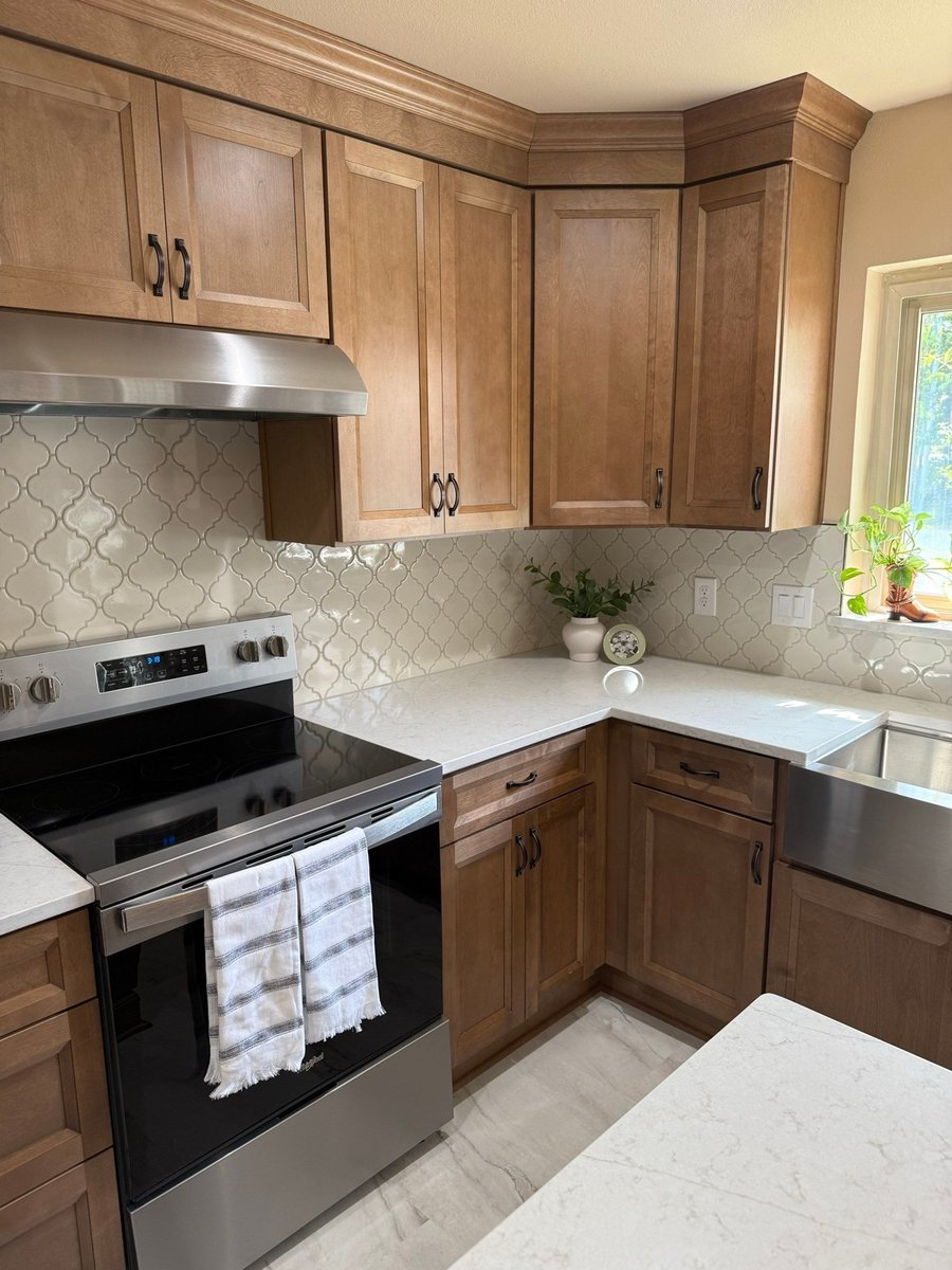 Wood cabinet kitchen corner with electric range and arabesque tile backsplash