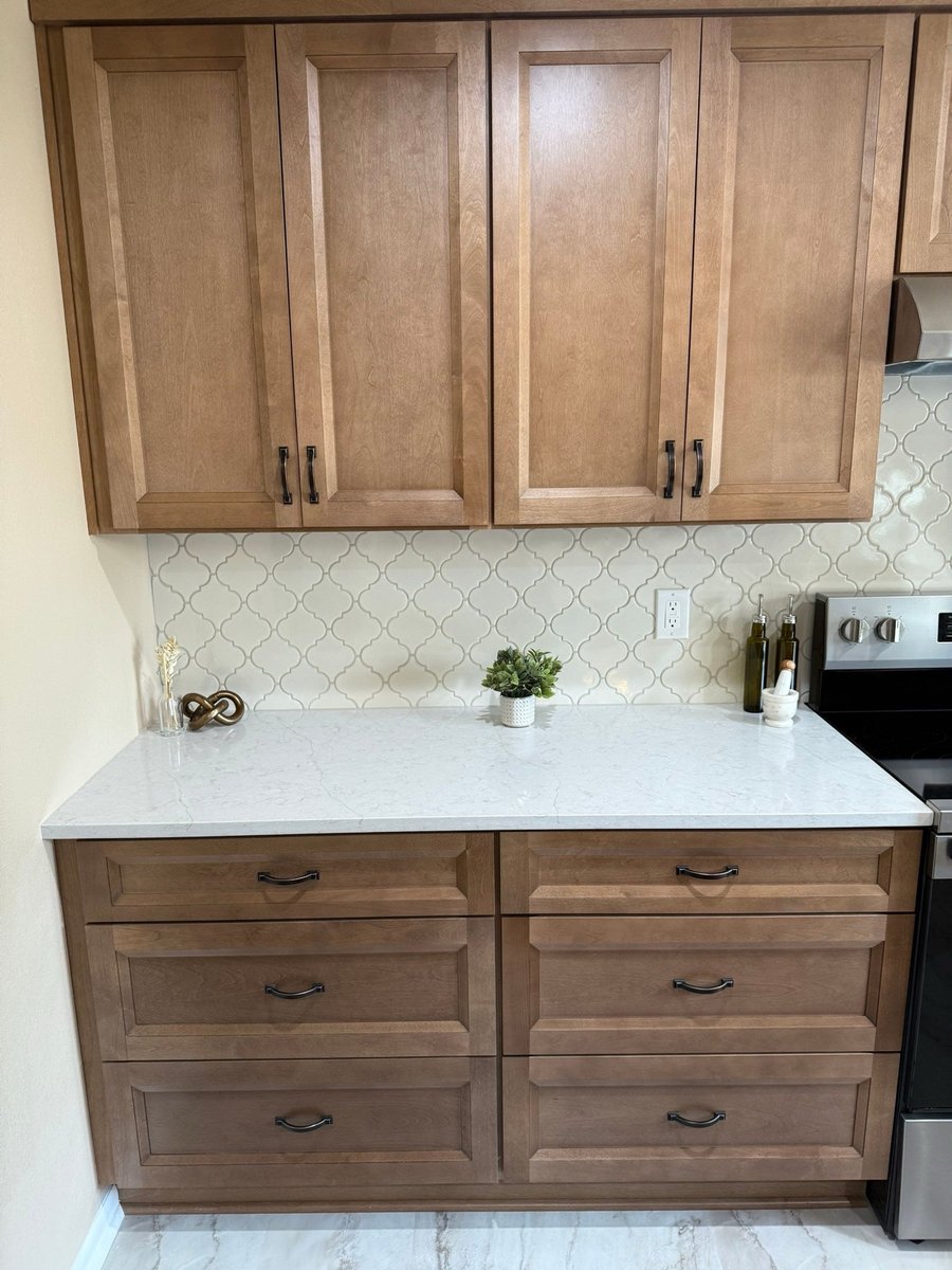 Wood lower cabinets with quartz counter and white arabesque tile backsplash