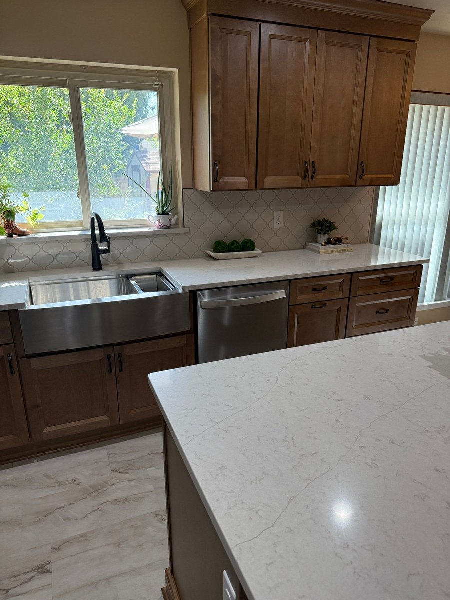 Stained wood cabinets with stainless farmhouse sink and white quartz island