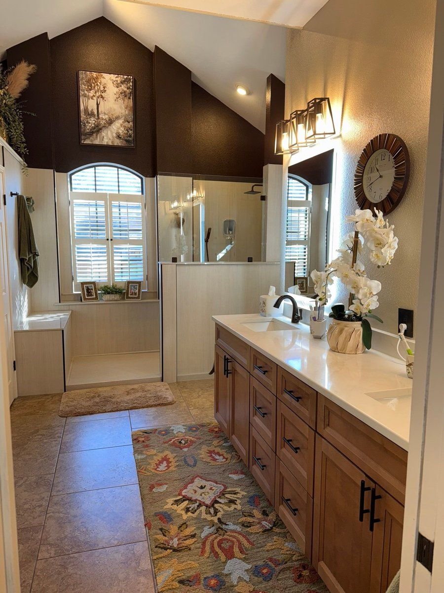 Master bath with double wood vanity, accent rug and open walk-in shower