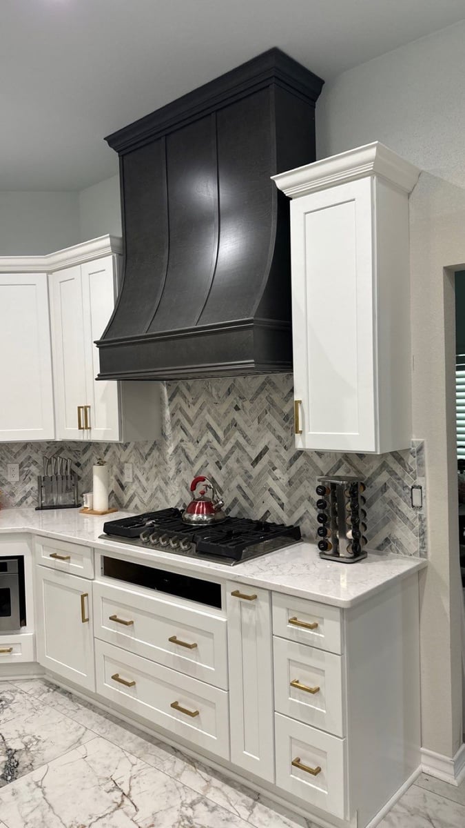 White kitchen with black wood range hood, herringbone backsplash, and white marble countertops
