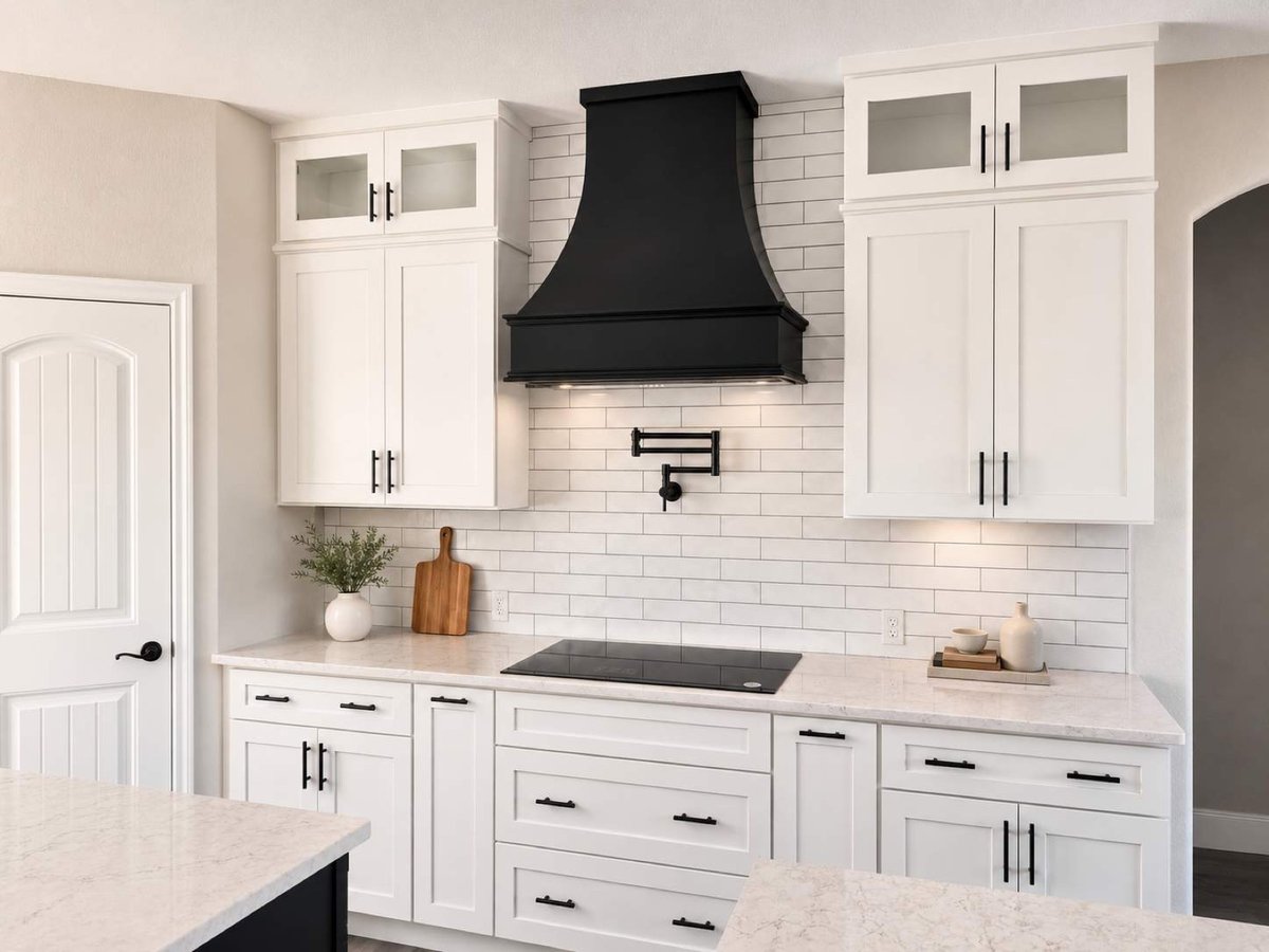 White kitchen with black range hood, subway tile and pot filler over cooktop