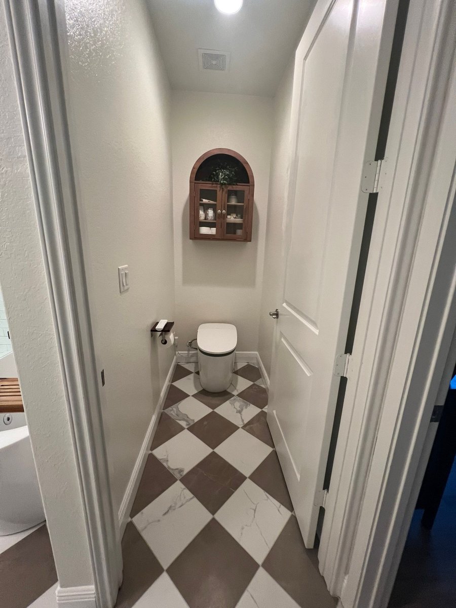 Private toilet alcove with checkered marble floor and arched wall cabinet