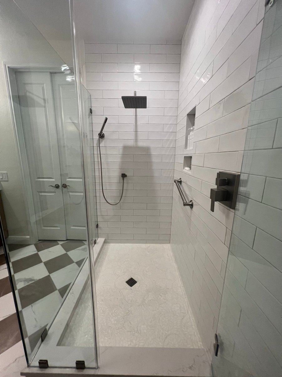Subway tile shower wall with black rain head, handheld sprayer and grab bar
