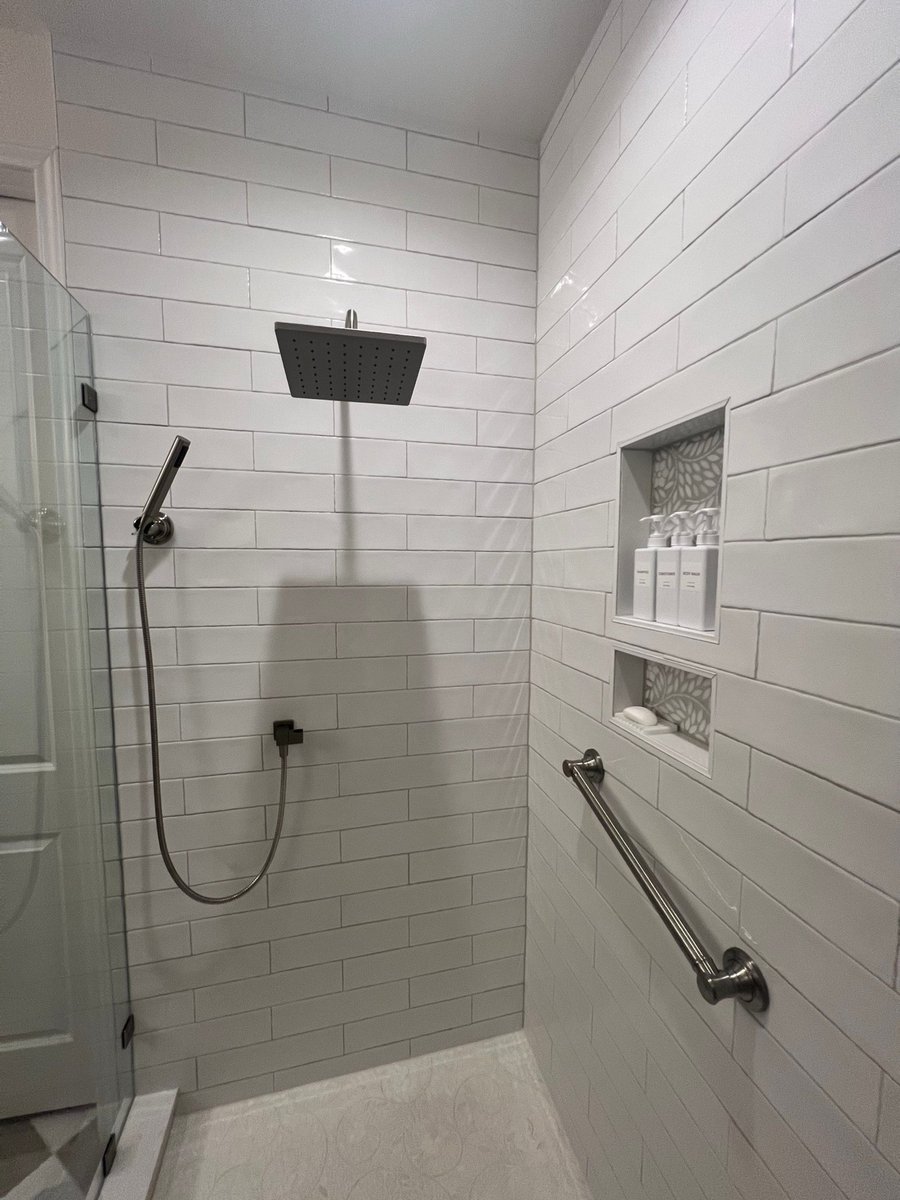 Recessed shower niches with floral mosaic backing holding labeled toiletry bottles