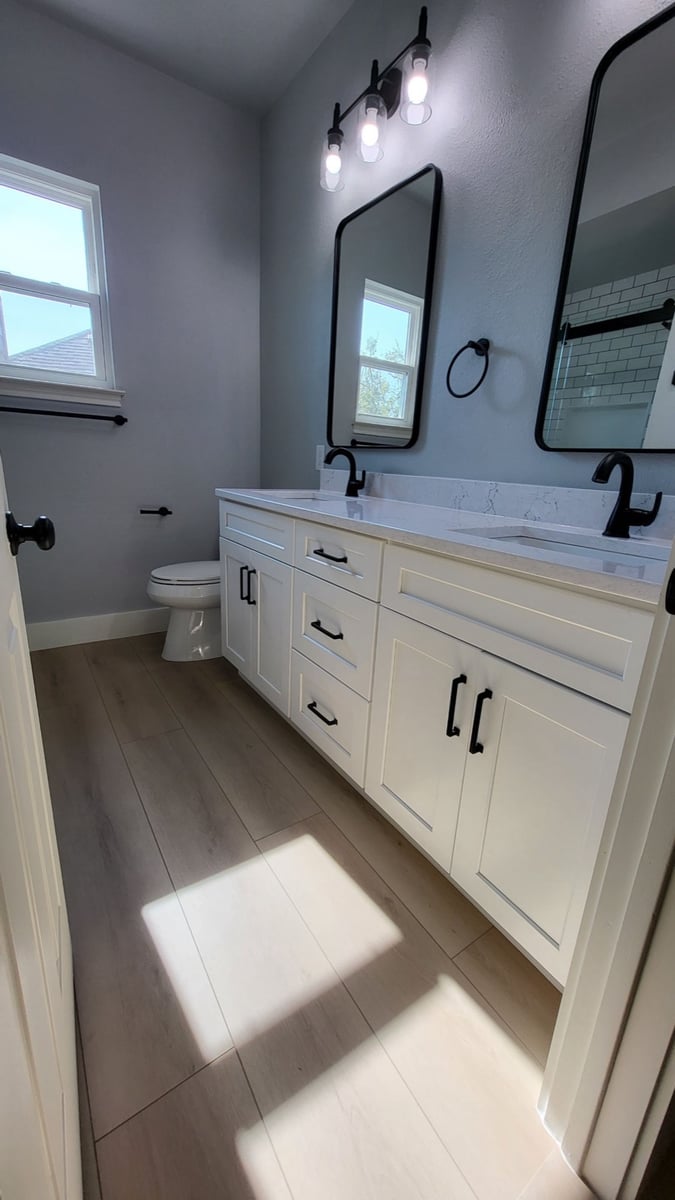 Gray bathroom with white double vanity, black fixtures and framed mirrors