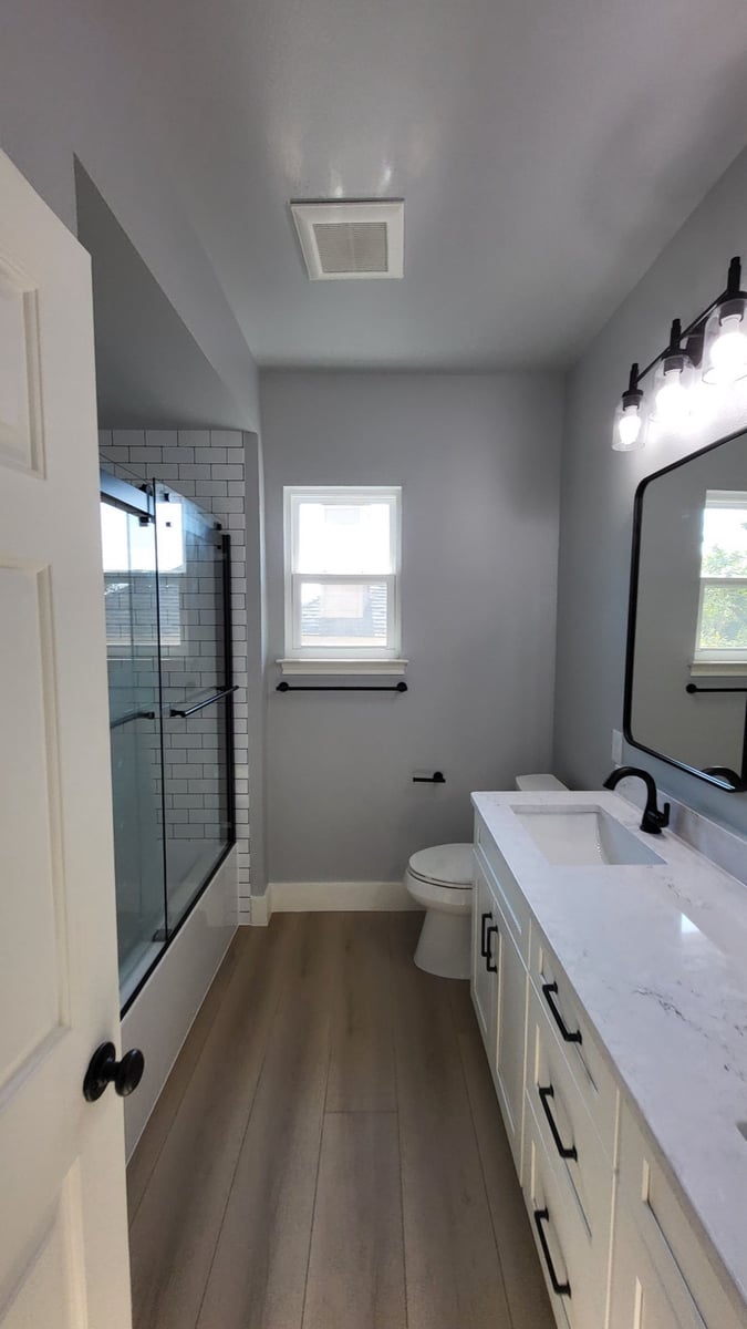 Bathroom with white subway-tiled tub-shower, gray walls and quartz vanity