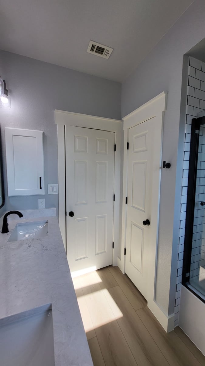Bathroom with white doors, quartz double vanity and subway-tiled shower