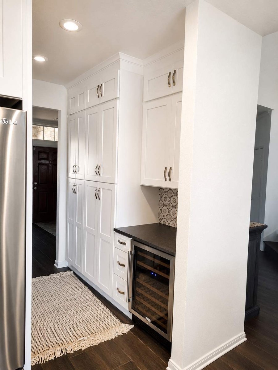 White pantry cabinets with built-in stainless wine fridge and dark wood floors