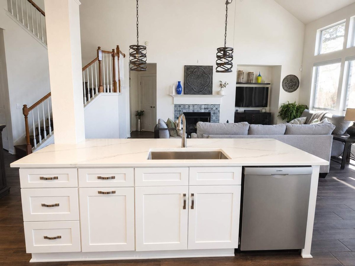 White quartz island with farmhouse sink overlooking living room with tiled fireplace