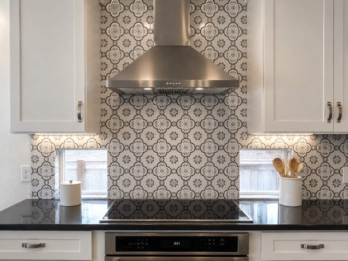 Stainless range hood against bold black and white patterned tile over electric cooktop