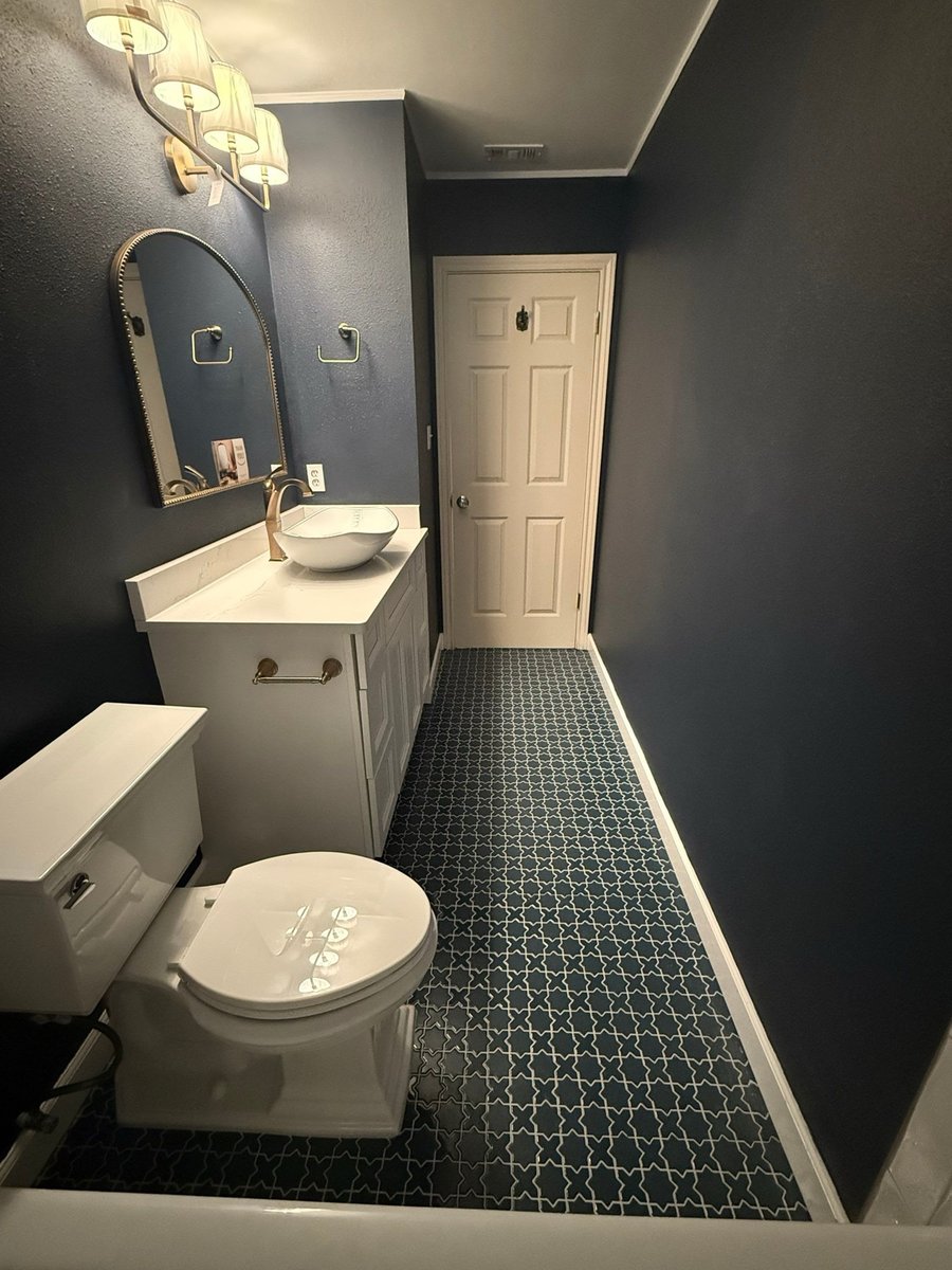 Navy guest bath with white vanity, vessel sink and patterned tile floor