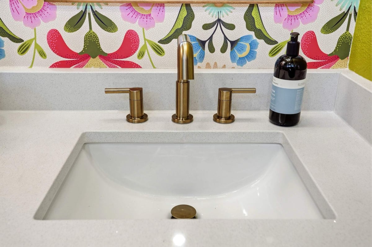 Detail of brass widespread faucet over a white undermount quartz sink