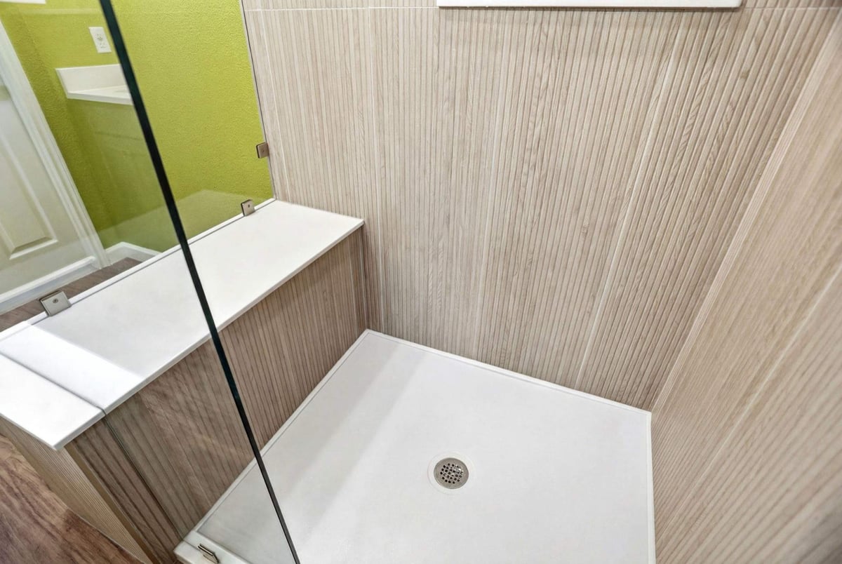 Wood-look tile shower stall with white base, glass panel, and green walls
