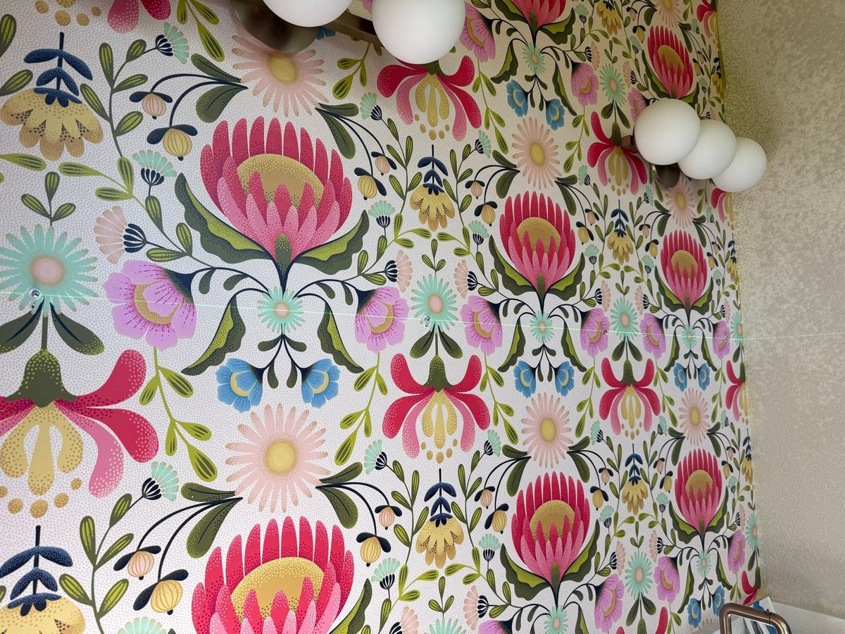 Close-up of vivid pink and green protea floral wallpaper with globe sconce