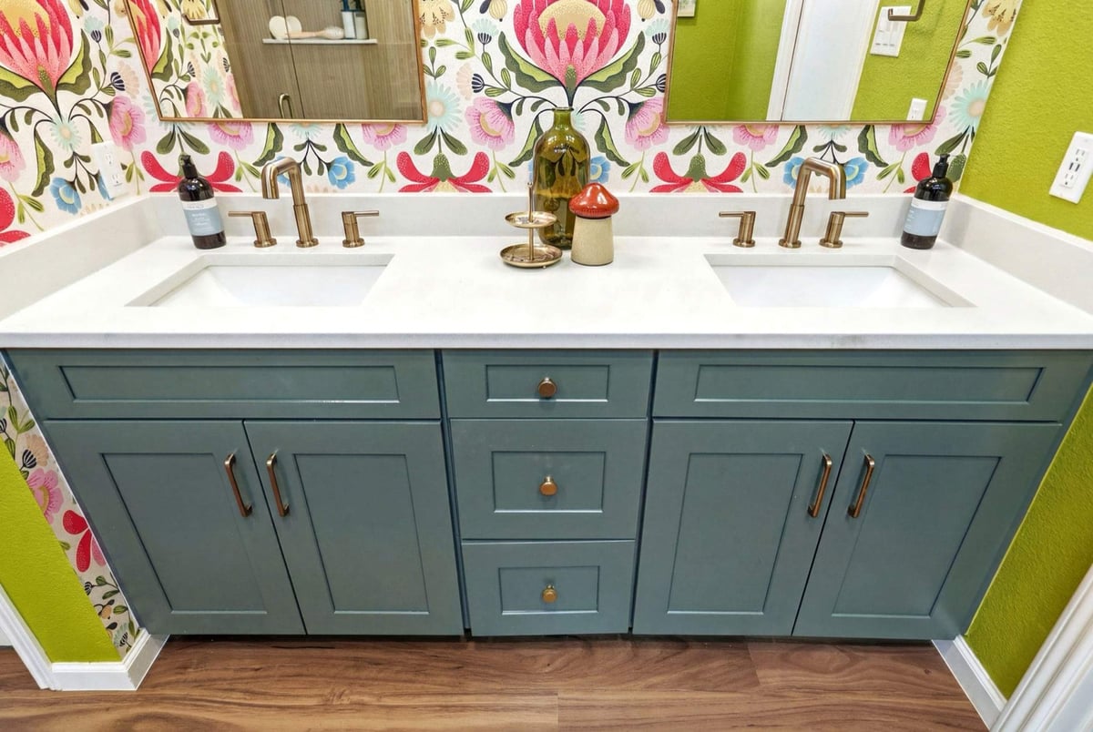 Teal shaker double vanity with brass pulls below floral protea wallpaper