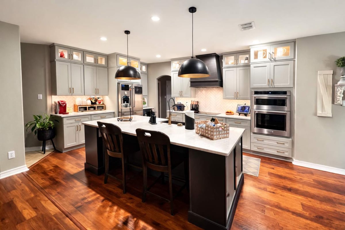 Remodeled kitchen with island seating, dark wood vent hood and double wall ovens