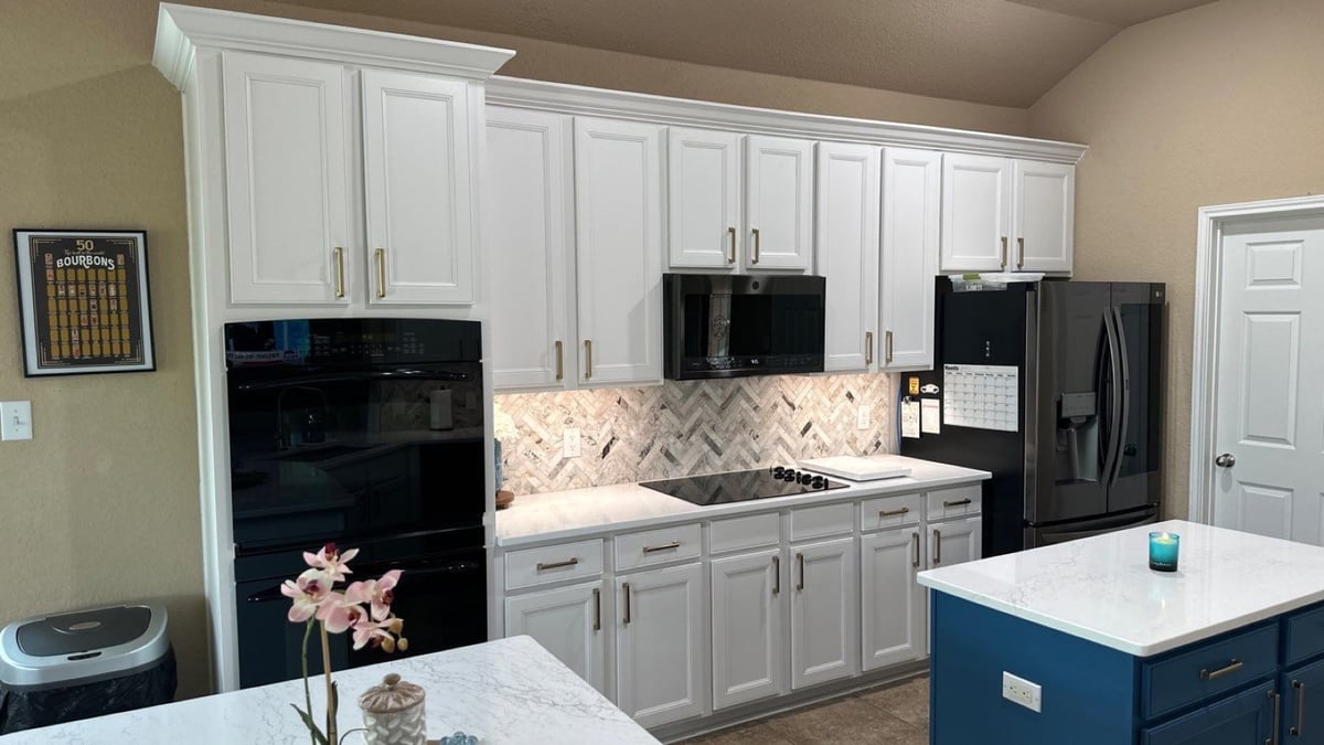 Refreshed kitchen with white cabinets, herringbone backsplash, and black appliances