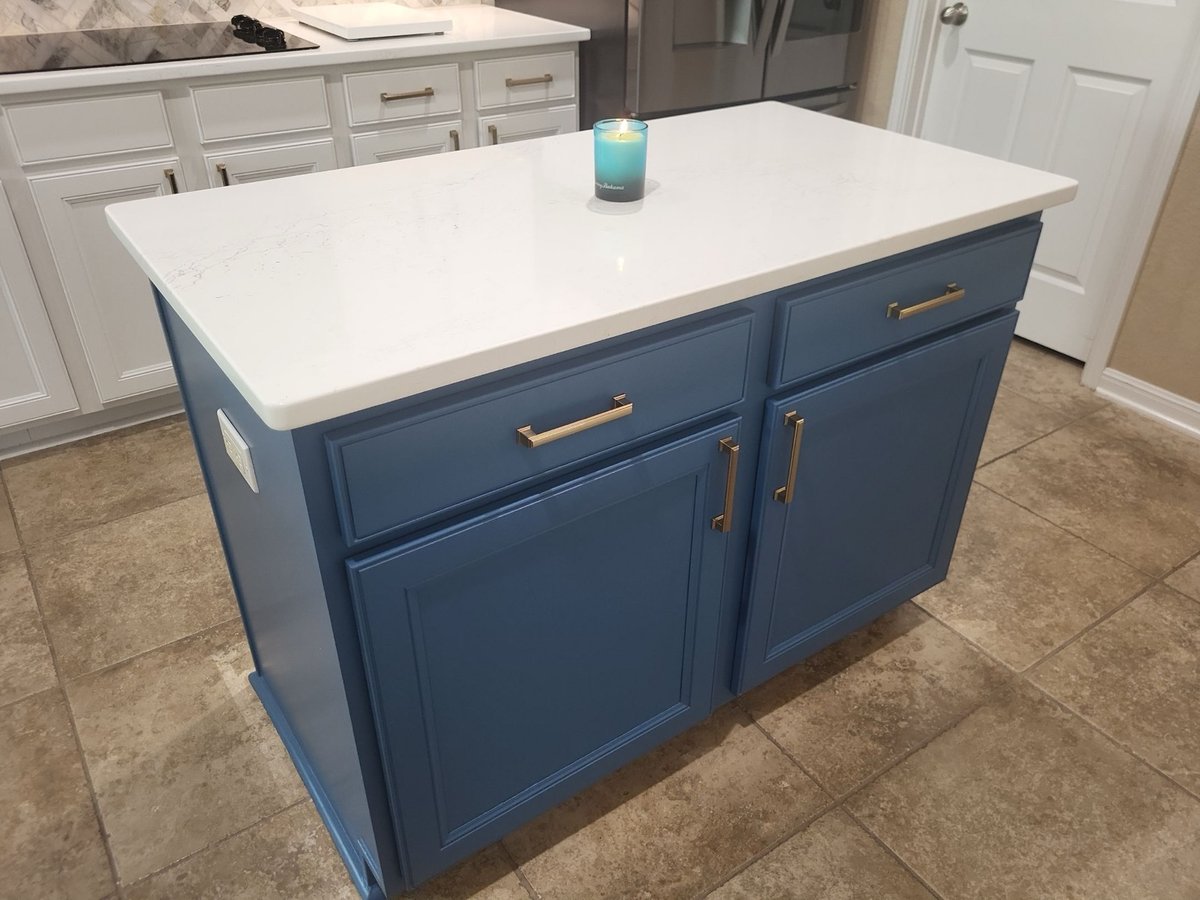 Navy blue kitchen island with white quartz top and brass cabinet handles