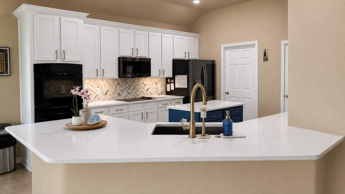 Bright kitchen with white quartz peninsula, white cabinets, and navy island