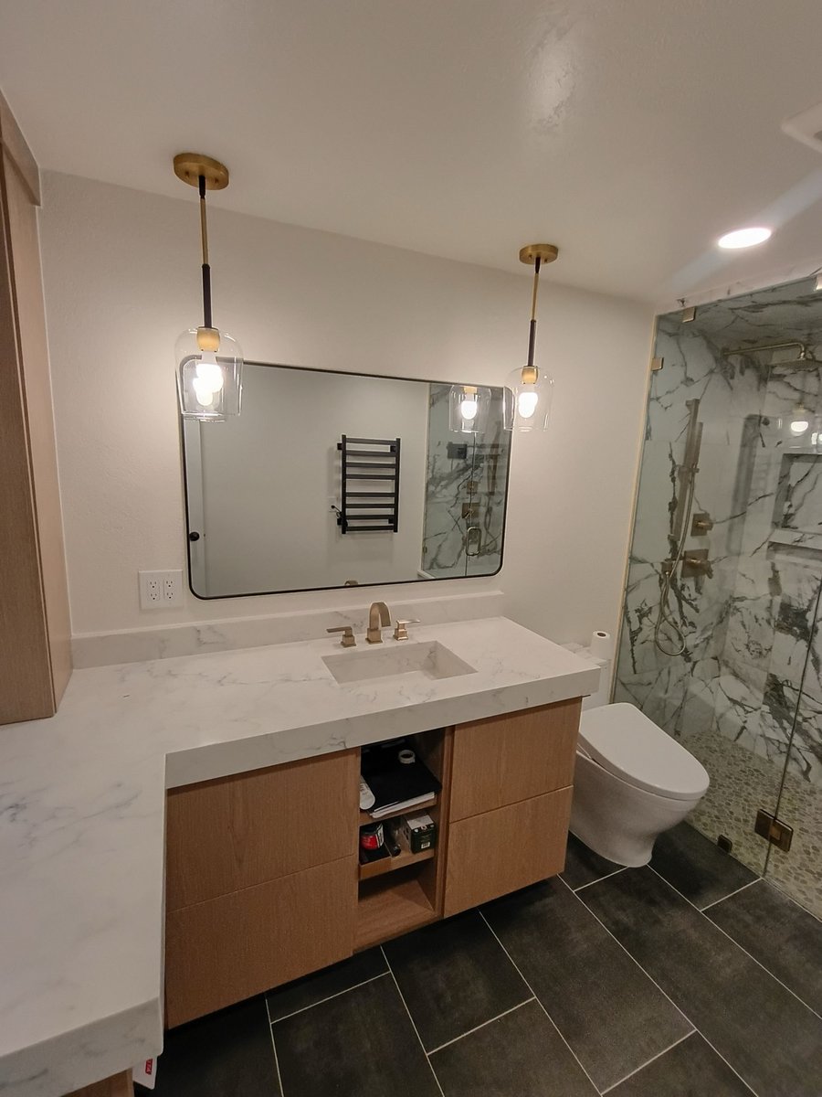 Master bath vanity with white marble counter, wood cabinets, and brass pendant lighting