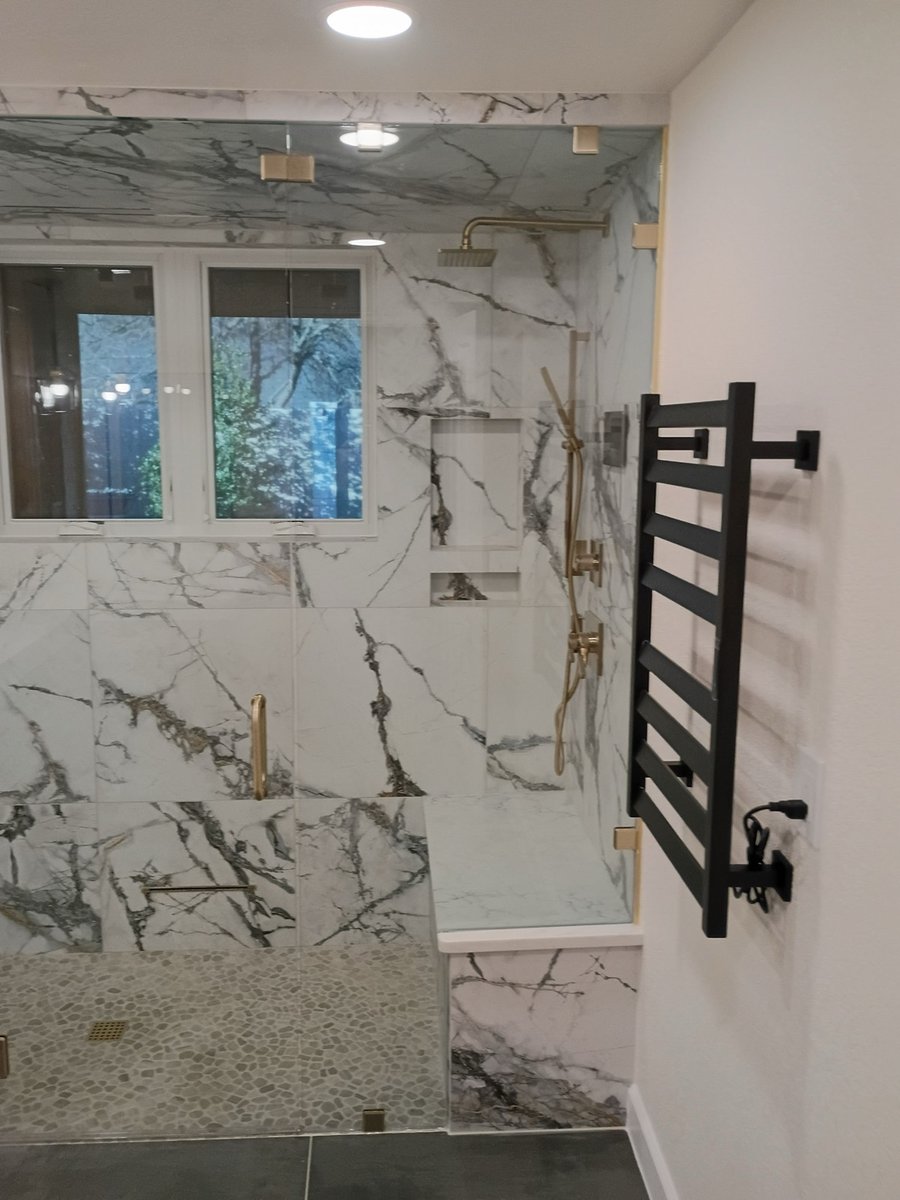 Shower interior with built-in marble bench, niche, and black towel warmer on wall